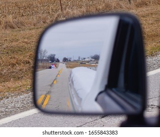 Rearview Mirror With Police Lights Flashing On The Highway