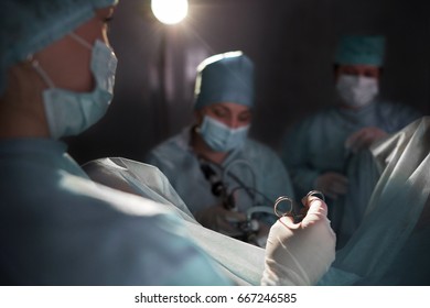 Rearview shot of a surgeon working with his team performing surgery on a patient healthcare medicine emergency urgency treatment concept.