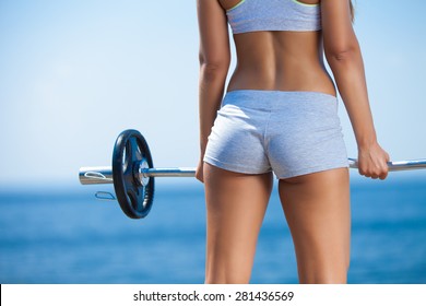 Rearview shot of a young woman doing squats with a barbell outside - Powered by Shutterstock