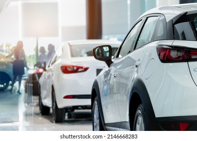Rearview white SUV car in modern luxury showroom on blur saleswoman and customer. Car dealership office concept. Dealer agent business. Automobile leasing service. Dealer company. New car purchase.