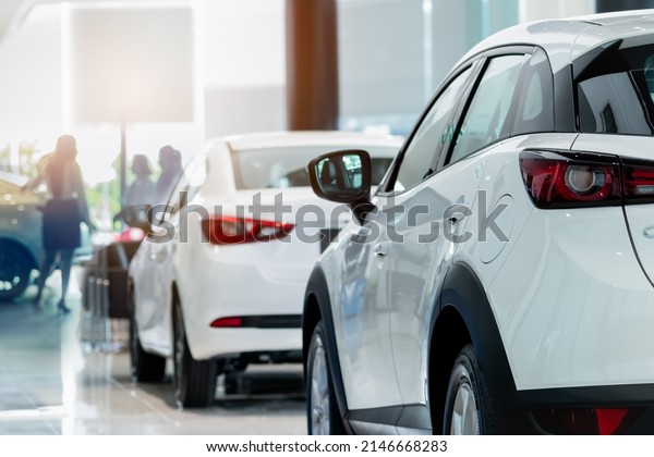 Rearview white SUV car in modern luxury\
showroom on blur saleswoman and customer. Car dealership office\
concept. Dealer agent business. Automobile leasing service. Dealer\
company. New car\
purchase.