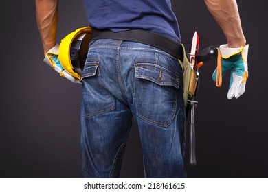 Rearview Of A Worker With Toolbelt And Helmet Against Black Background