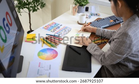 reative designer developing branding idea with color pencils, palette, and digital tablet.