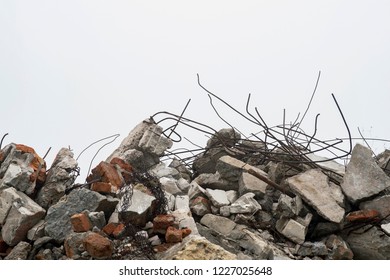 The rebar sticking up from piles of brick rubble, stone and concrete rubble against the sky in a haze. Remains of the destroyed building. Copy space.