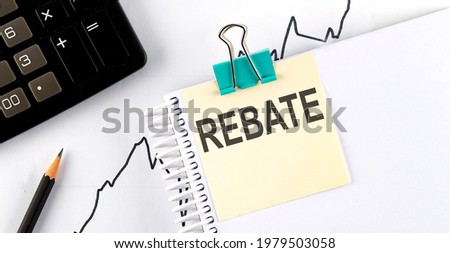 REBATE text, written on a sticker with calculator,pencil on the chart background.