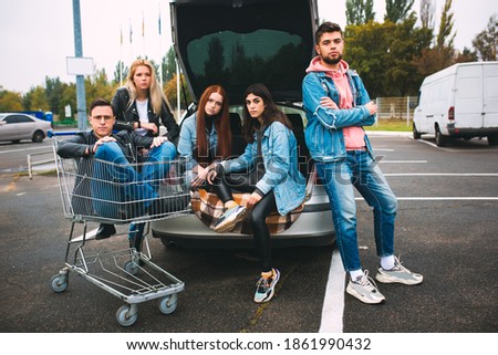 Rebel. Group of four young diverse friends in jeanse outfit look carefree, young and happy walking down the city's streets. Fashion of urban clothes, freedom, friendship, style concept.