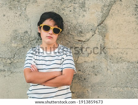 rebellious boy with sunglasses next to a wall outdoors