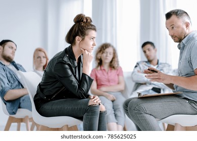 Rebellious young girl listening to her counselor during appointment with problematic teenagers