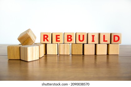 Rebuild And Build Symbol. The Concept Word Rebuild On Wooden Cubes. Beautiful Wooden Table, White Background, Copy Space. Business Rebuild And Build Concept.