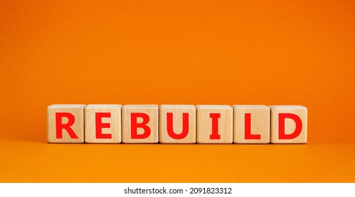 Rebuild And Build Symbol. The Concept Word Rebuild On Wooden Cubes. Beautiful Orange Table, Orange Background, Copy Space. Business Rebuild And Build Concept.