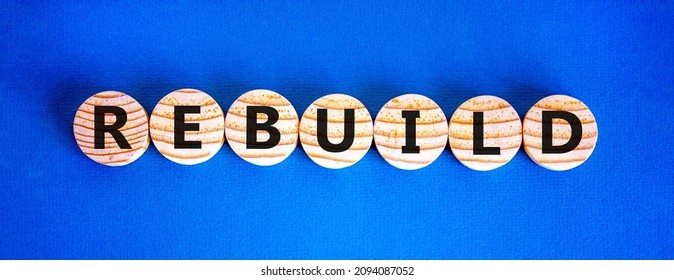 Rebuild And Build Symbol. The Concept Word Rebuild On Wooden Circles. Beautiful Blue Background, Copy Space. Business Rebuild And Build Concept.