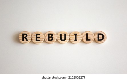 Rebuild And Build Symbol. The Concept Word Rebuild On Wooden Circles. Beautiful White Background, Copy Space. Business Rebuild And Build Concept.