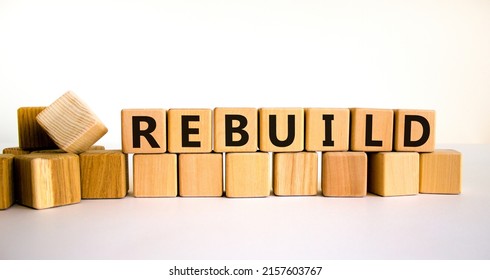 Rebuild and build symbol. The concept word Rebuild on wooden cubes. Beautiful white table, white background, copy space. Business rebuild and build concept.