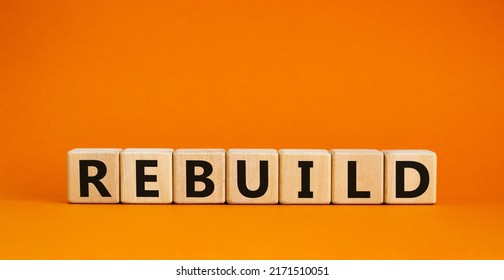 Rebuild And Build Symbol. The Concept Word Rebuild On Wooden Cubes. Beautiful Orange Table, Orange Background, Copy Space. Business Rebuild And Build Concept.