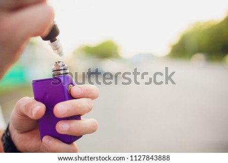 Rebuildable dripping atomizer or RDA for vaping or e-cigarette with coil and cotton stripes wetted with e-liquid, modern vape device for quit smoking, macro photo with selective focus