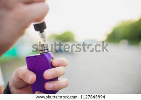 Rebuildable dripping atomizer or RDA for vaping or e-cigarette with coil and cotton stripes wetted with e-liquid, modern vape device for quit smoking, macro photo with selective focus