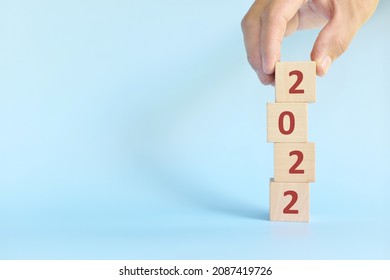 Rebuilding new year 2022 concept. Hand stacking building blocks with 2022 number in blue background.