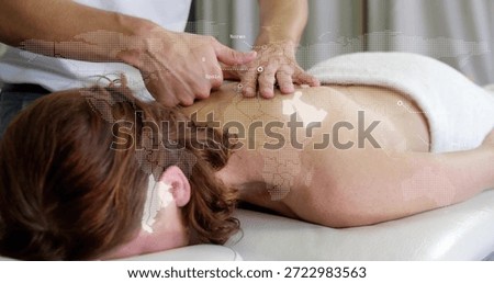 Receiving client lying prone at spa, towel draping hips, therapist kneading neck, dotted map. Massage, therapy, relaxation, wellness, calm, serene, lighting