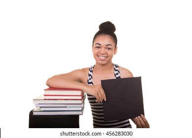 Recent College Graduate In A Cap And Gown Next To A Stack Of Books
