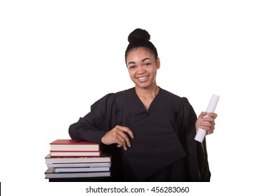 Recent College Graduate In A Cap And Gown Next To A Stack Of Books
