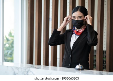 Reception Employee Wearing Her Protective Mask And Smiling At The Luxury Modern Reception Hotel Desk.