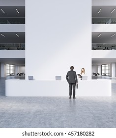 Reception in modern office. Man and woman in suits standing in front of big white table with computers. Chairs and other rooms in background. Concept of business meeting. 3d rendering. Mock up