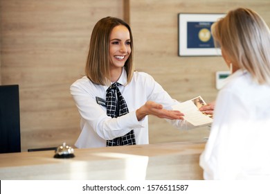 Receptionist And Businesswoman At Hotel Front Desk