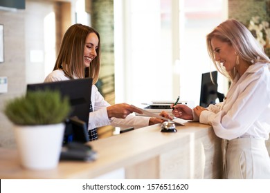 Receptionist And Businesswoman At Hotel Front Desk