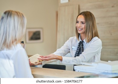 Receptionist And Businesswoman At Hotel Front Desk