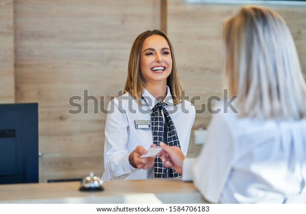 Receptionist and\
businesswoman at hotel front\
desk