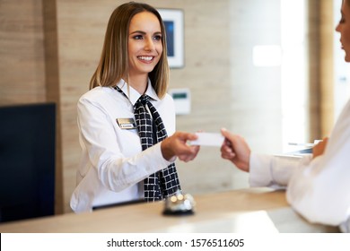 Receptionist Giving Key Card To Businesswoman At Hotel Front Desk