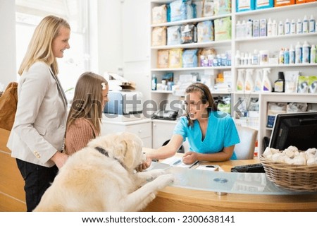 Receptionist greeting dog in vet's surgery