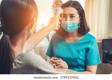 Receptionist And Guest Wearing Face Mask At Front Desk While Having Conversation In Office Or Hospital . Covid 19 And Coronavirus Infection Protection And Protective Policy Concept .