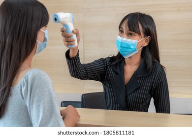 Receptionist And Guest Wearing Face Mask At Front Desk While Having Conversation In Office Or Hospital . Covid 19 And Coronavirus Infection Protection And Protective Policy Concept .