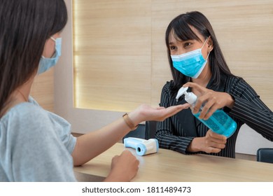 Receptionist And Guest Wearing Face Mask At Front Desk While Having Conversation In Office Or Hospital . Covid 19 And Coronavirus Infection Protection And Protective Policy Concept .