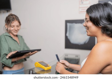 Receptionist of optical store attending a woman using digital tablet - Powered by Shutterstock