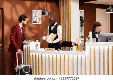 Receptionist providing luxury service to help businessman at registration front desk, african american hotel concierge greeting professional client. International business conference abroad. - Powered by Shutterstock