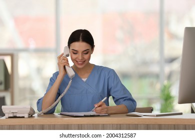 Receptionist talking on phone at countertop in hospital - Shutterstock ID 2004312587