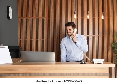 Receptionist talking on phone at desk in lobby