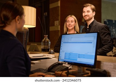 Receptionist typing on computer while couple standing at reception desk