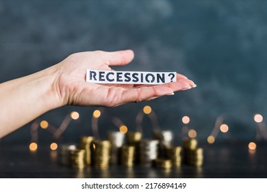 recession and inflation after the Covid-19 pandemic conceptual image, hand holding Recession text in front of stacks of coins with fairy lights in the background - Shutterstock ID 2176894149