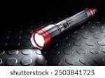 Rechargeable black and red metal flashlight with its LED activiated that is ideal for power outages, hurricanes of other natural disasters.