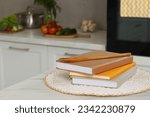 Recipe books and wooden spoon on white marble table in kitchen, closeup. Space for text