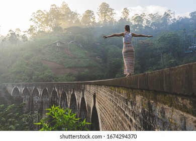 reckless woman walking on the edge of the nine-arches bridge in Sri Lanka