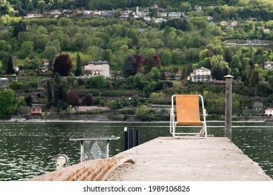 Recliner Chair On A Pier With Water And Hills On Background.