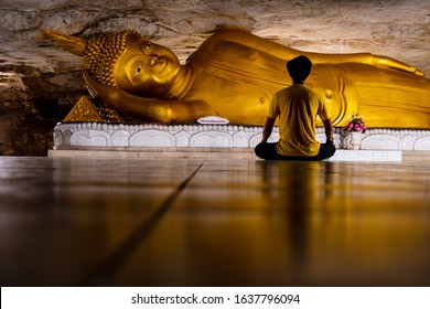 Reclining Buddha gold statue face at Loei. Thailand. The Buddha statue in the cave. The man sitting in front - Powered by Shutterstock