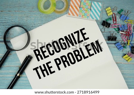 Recognize The Problem text on a paper surrounded by office supplies and magnifying glass on a blue wooden surface