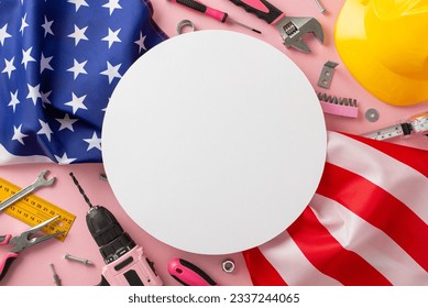 Recognizing the contributions of women in labor on Labor Day. High-angle photo showcasing a pink backdrop, an American flag, and building tools, with copyspace inside a circle for ads or text - Powered by Shutterstock