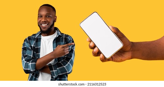 Recommendation. Portrait of cheerful black guy pointing finger at big blank cell phone screen, hand holding device with white empty display. Gadget with free space for mock up, banner panorama