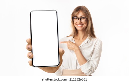 Recommendation. Portrait Of Excited Business Woman In Glasses Holding Big Smartphone With White Screen In Hand, Showing Close To Camera Pointing At Device. Gadget With Free Space For Mock Up, Banner